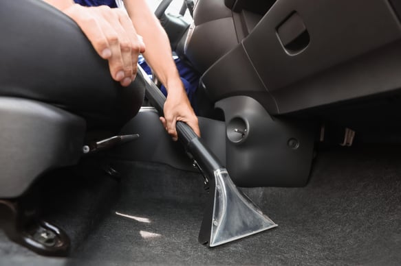 Man cleaning automobile salon with vacuum cleaner, closeup. Car wash service