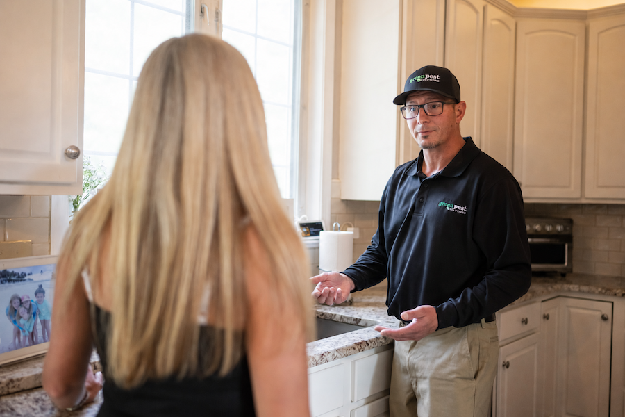 pest technician in kitchen with customer